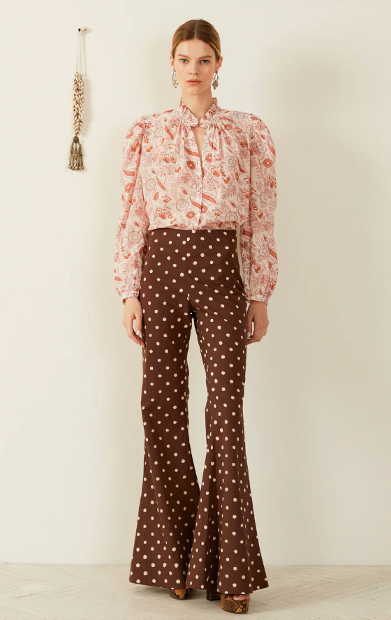 A woman wearing a Alix of Bohemian pink blouse and brown polka dot pants