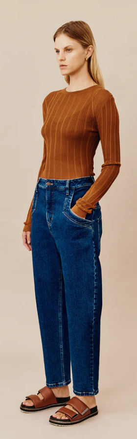 A woman wearing a dark orange Ginger and Smart shirt with blue jeans