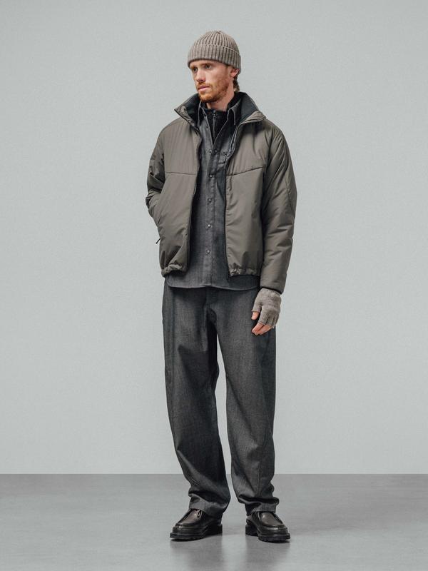 A model in a stone-grey insulated jacket over a grey shirt and wide grey trousers