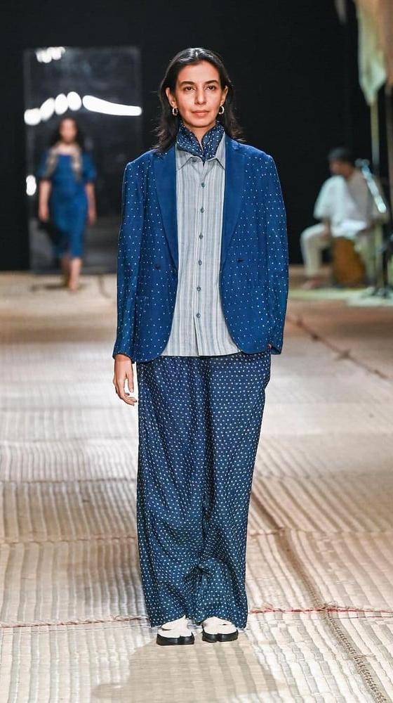 A woman wearing an indigo hand-woven 11.11 / eleven eleven jacket and wide-leg trousers