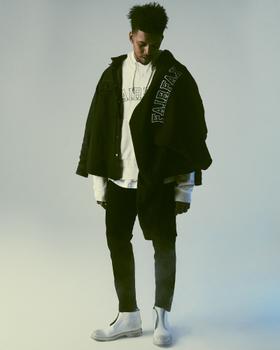 A man wearing a black 424 Fairfax overshirt layered over a white FAIRFAX hoodie with black trousers and white boots