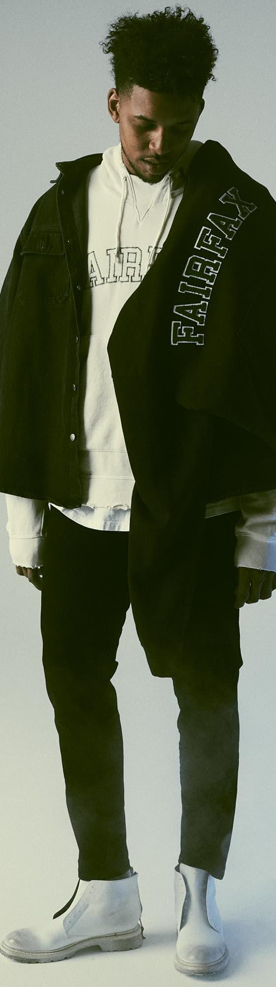 A man wearing a black 424 Fairfax overshirt layered over a white FAIRFAX hoodie with black trousers and white boots