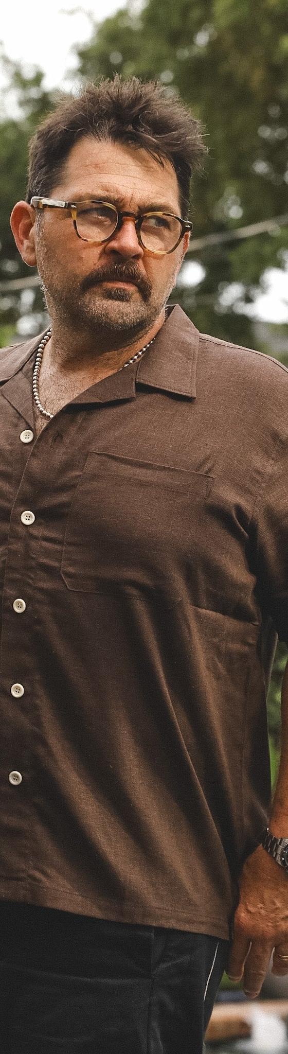 A man wearing a brown A New Medium camp collar shirt