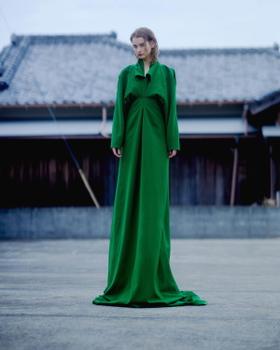 A woman wearing a floor-length emerald green draped AKIKOAOKI dress