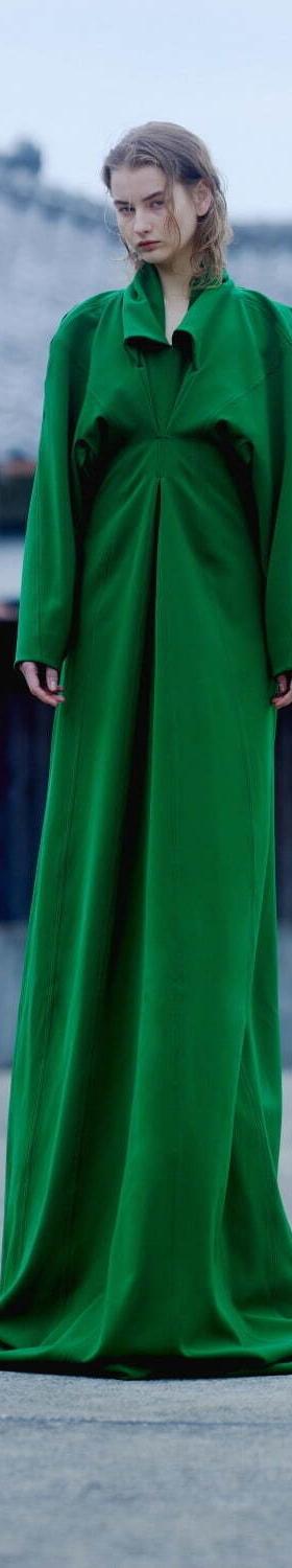 A woman wearing a floor-length emerald green draped AKIKOAOKI dress