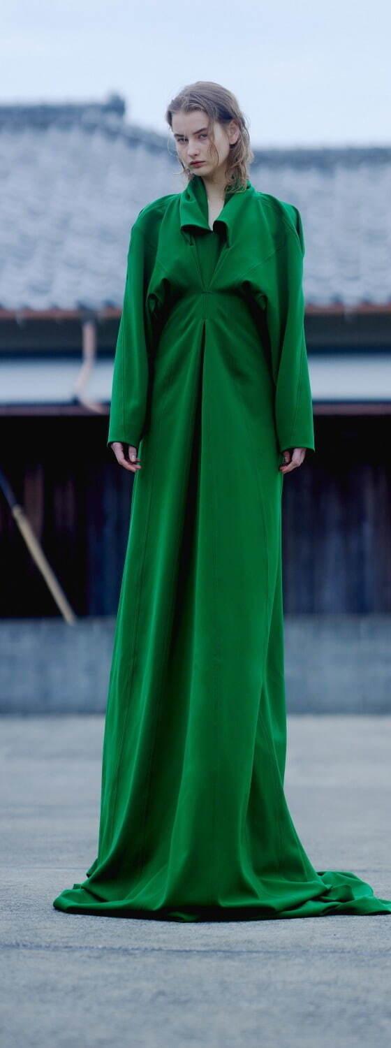 A woman wearing a floor-length emerald green draped AKIKOAOKI dress