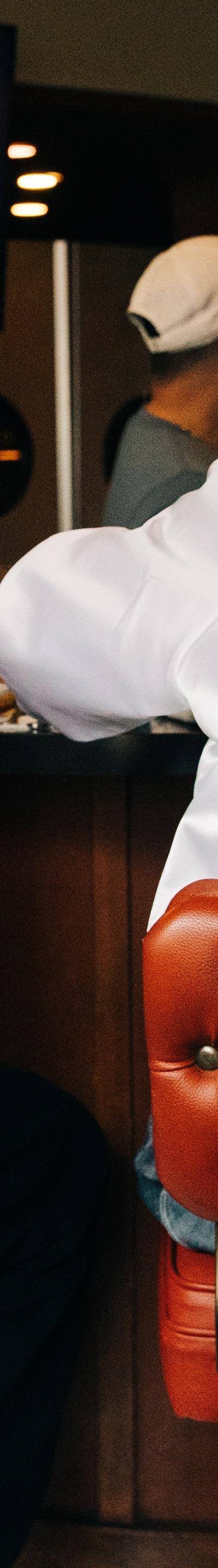 Two people seated at a diner counter wearing Alive & Well satin coach jackets
