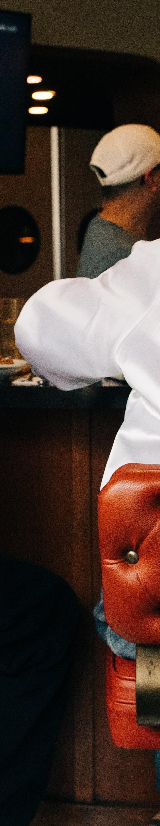 Two people seated at a diner counter wearing Alive & Well satin coach jackets