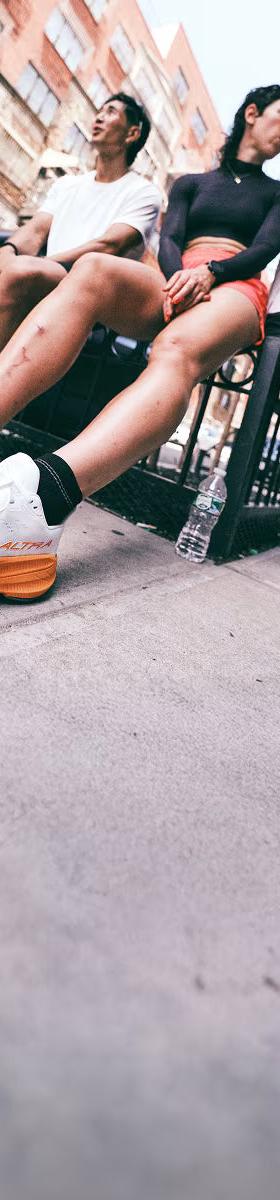 Three runners in Altra road running shoes sitting on a city street railing
