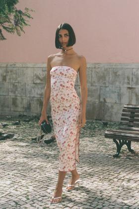 A woman wearing a floral-print strapless Amlul midi dress on a cobbled street