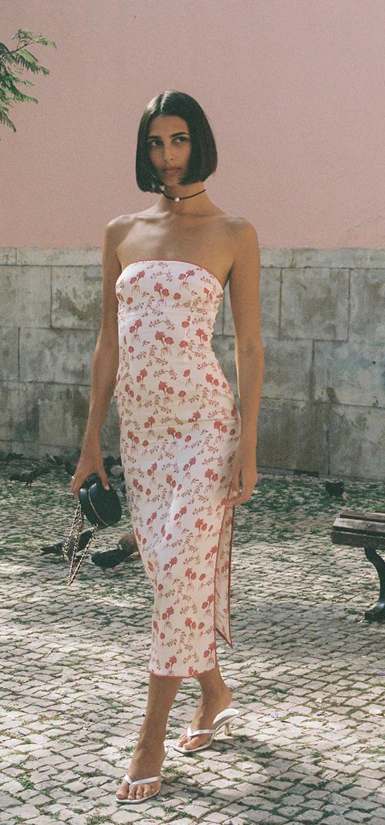 A woman wearing a floral-print strapless Amlul midi dress on a cobbled street
