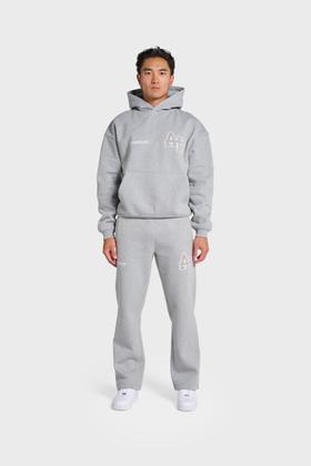 A man wearing a grey ANNIE HOOD monogrammed hoodie and matching sweatpants