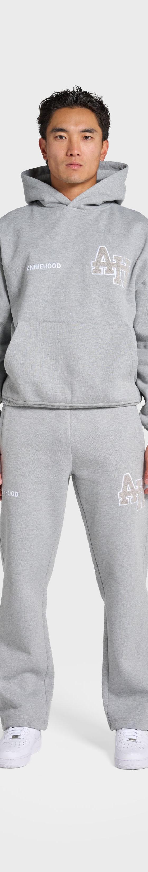 A man wearing a grey ANNIE HOOD monogrammed hoodie and matching sweatpants