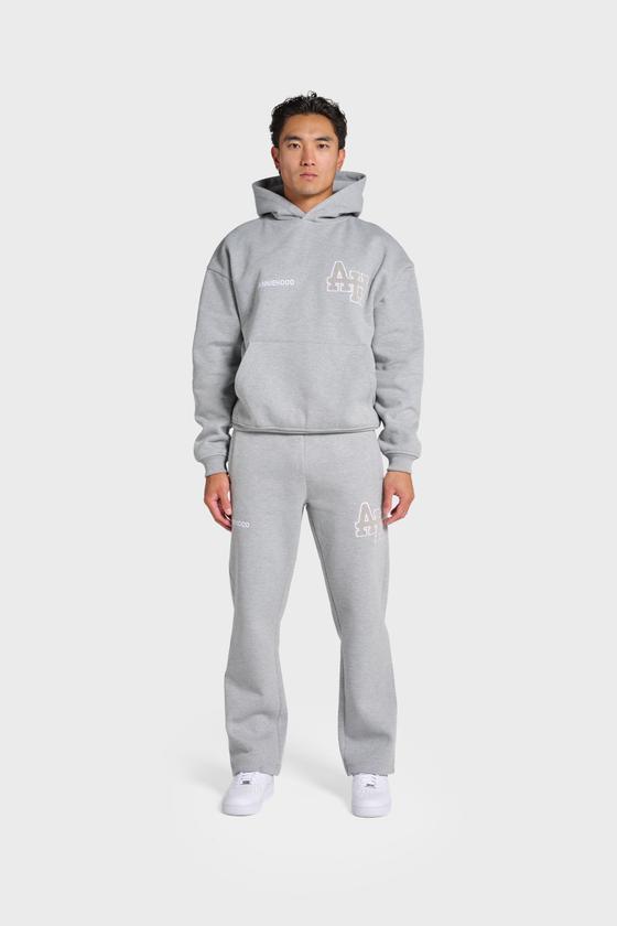 A man wearing a grey ANNIE HOOD monogrammed hoodie and matching sweatpants