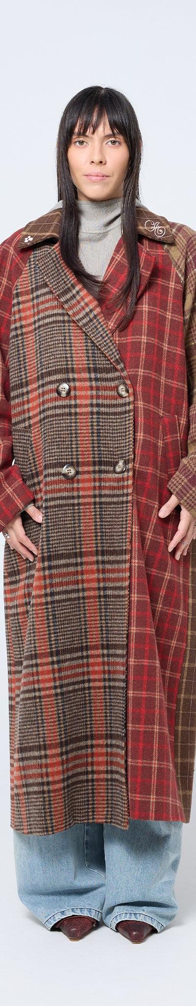 A woman wearing a red and brown patchwork checked Arthur Apparel coat with wide-leg jeans