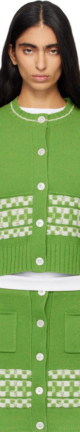 A woman wearing a green checkerboard-trimmed B.B. Wallace knit cardigan and matching skirt