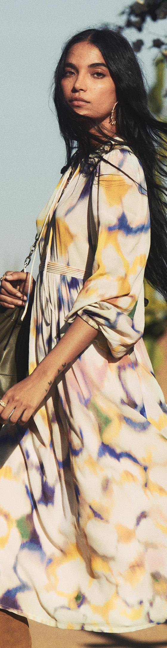 A woman wearing a floral-print ba&sh maxi dress with a green suede shoulder bag