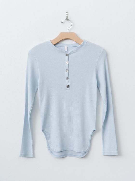 A pale blue babaco long-sleeve henley top on a wooden hanger against a white wall