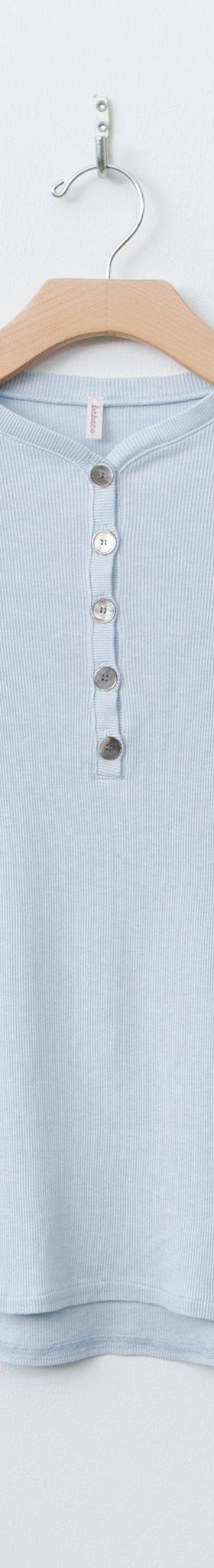 A pale blue babaco long-sleeve henley top on a wooden hanger against a white wall