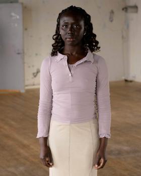 A woman wearing a lilac ribbed Baserange polo top with a cream knit skirt