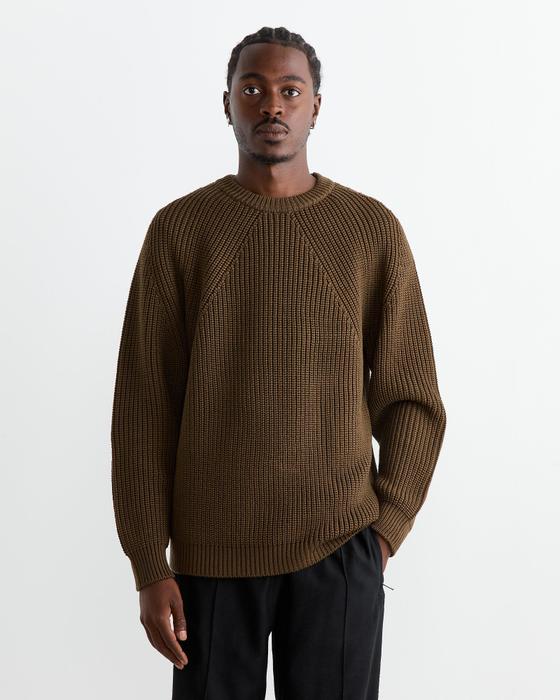 A man wearing a brown ribbed BATONER knit sweater with black trousers
