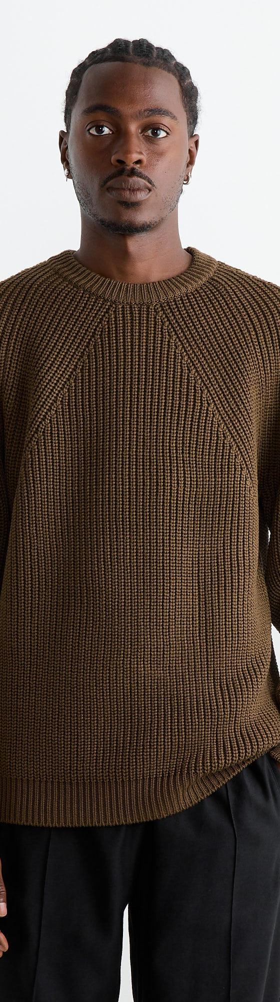 A man wearing a brown ribbed BATONER knit sweater with black trousers