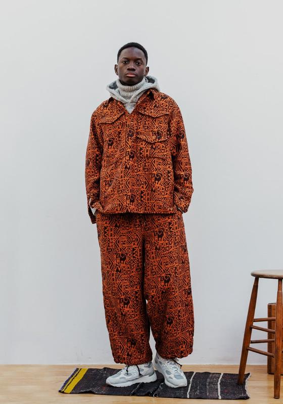A man wearing a patterned rust-orange BEAMS JAPAN overshirt and matching wide trousers