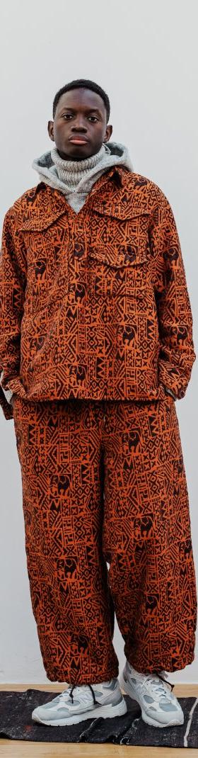A man wearing a patterned rust-orange BEAMS JAPAN overshirt and matching wide trousers