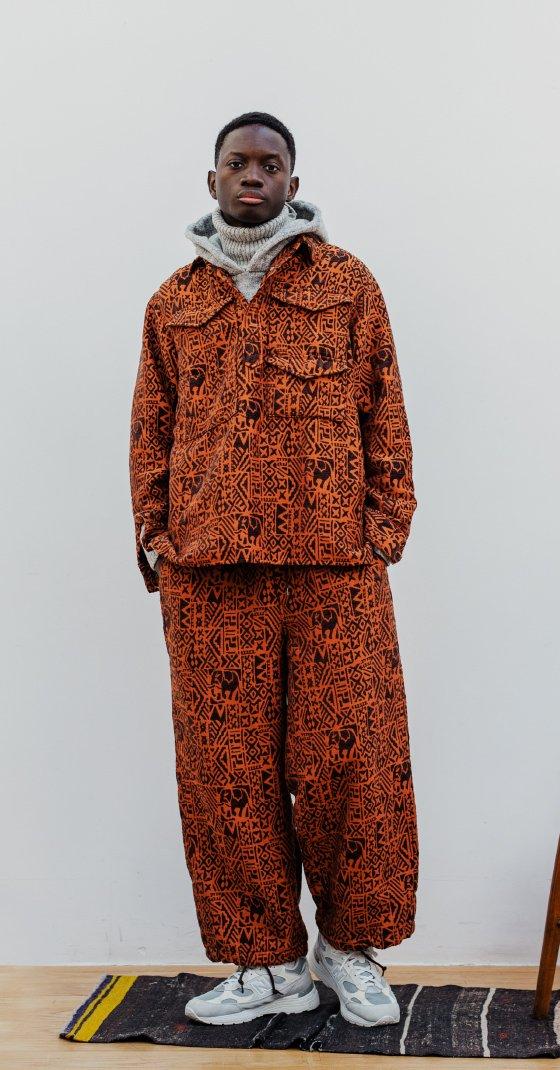 A man wearing a patterned rust-orange BEAMS JAPAN overshirt and matching wide trousers