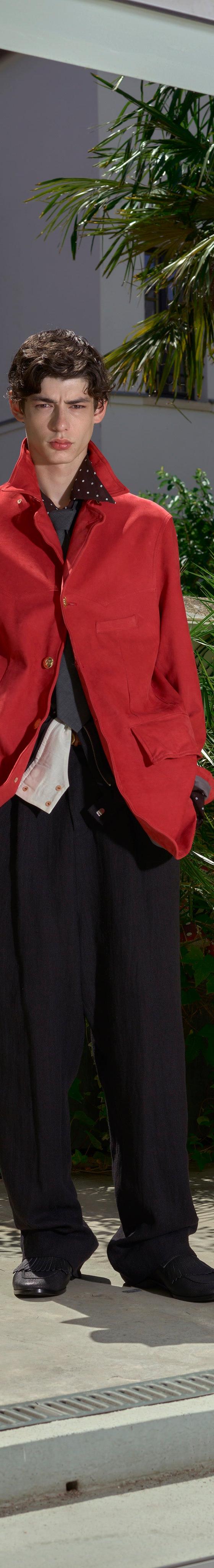 A man wearing a red draped BED j.w. FORD jacket with black wide-leg trousers