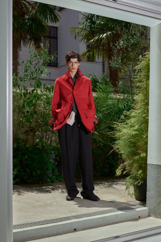 A man wearing a red draped BED j.w. FORD jacket with black wide-leg trousers