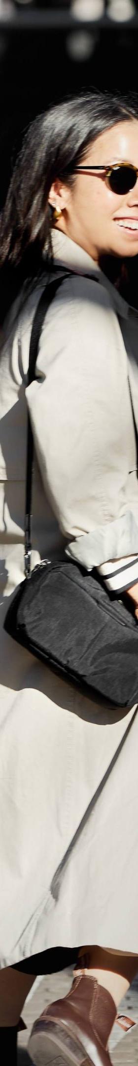A woman wearing a beige trench coat with a black Bellroy crossbody bag