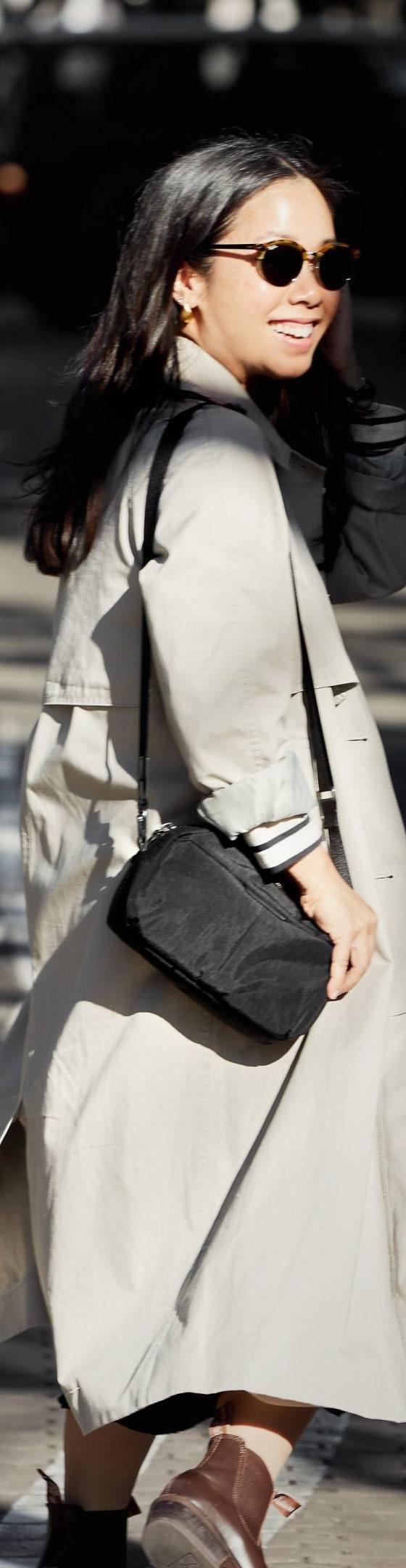 A woman wearing a beige trench coat with a black Bellroy crossbody bag