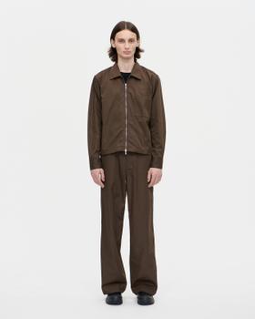 A man wearing a brown Berner Kühl zip overshirt with matching brown wide-leg trousers