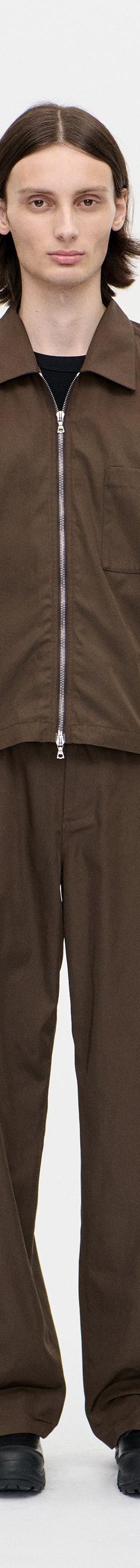 A man wearing a brown Berner Kühl zip overshirt with matching brown wide-leg trousers
