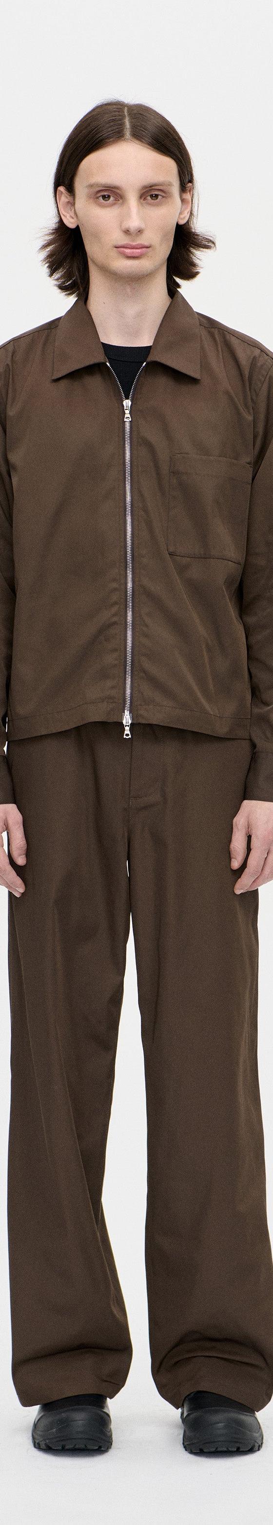 A man wearing a brown Berner Kühl zip overshirt with matching brown wide-leg trousers