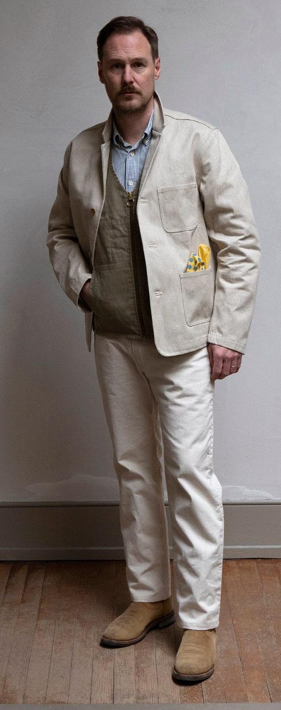 A man wearing a natural canvas Best Made Company chore jacket with matching trousers and suede boots