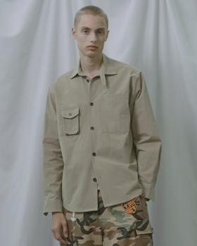 A man wearing a beige BEYOND CLOSET garment-dyed military overshirt