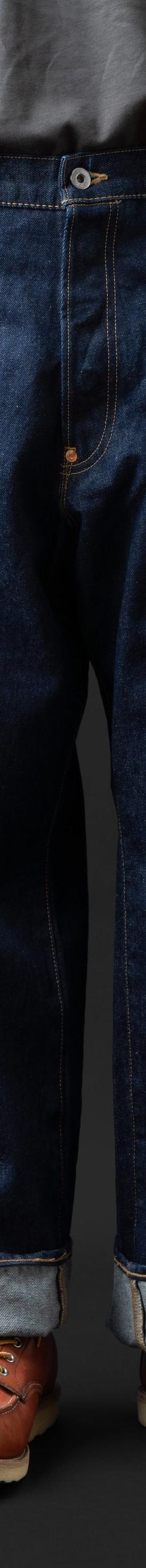 A man wearing wide-leg indigo BIG JOHN selvedge jeans with cuffed hems and brown leather moc-toe boots
