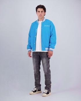 A man wearing a blue Black Bananas varsity bomber jacket