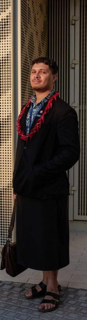 A man wearing a black Black Pearl Créations jacket with a red beaded necklace