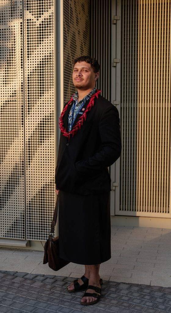 A man wearing a black Black Pearl Créations jacket with a red beaded necklace