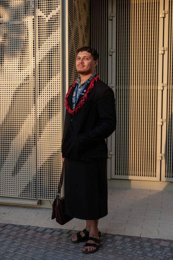 A man wearing a black Black Pearl Créations jacket with a red beaded necklace