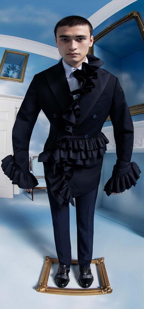 A man wearing a black double-breasted ruffled tailcoat and trousers