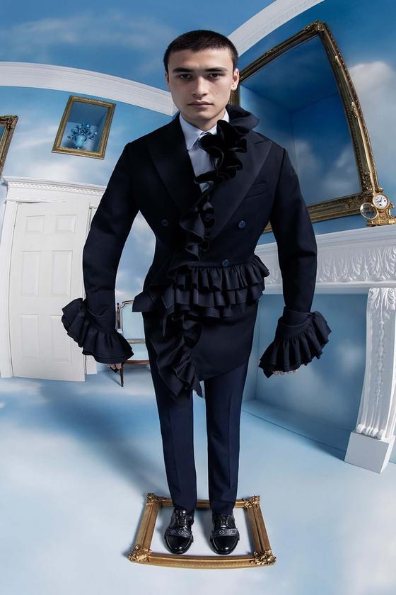 A man wearing a black double-breasted ruffled tailcoat and trousers