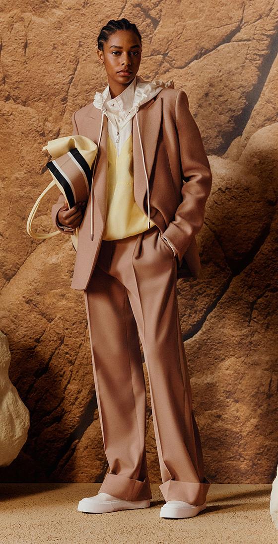 A woman wearing a camel BOSS tailored suit with a pale yellow knit