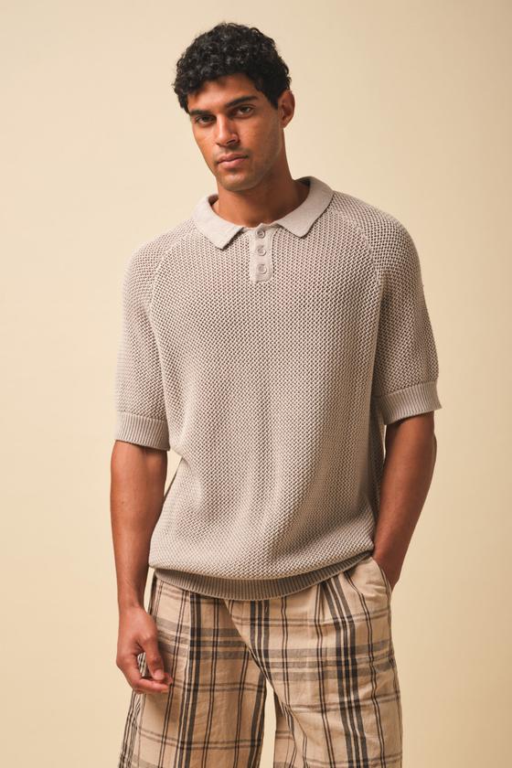 A man wearing a stone open-knit Bound polo shirt with checked trousers