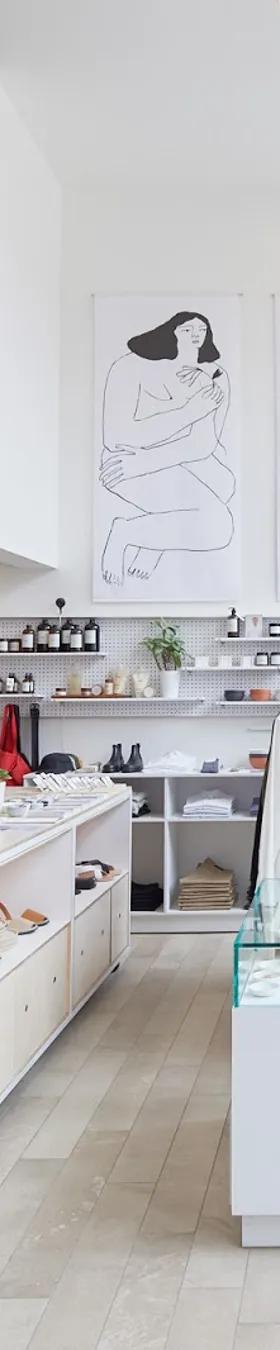The bright interior of a Montreal atelier-boutique with white racks of clothing and line-drawing artwork