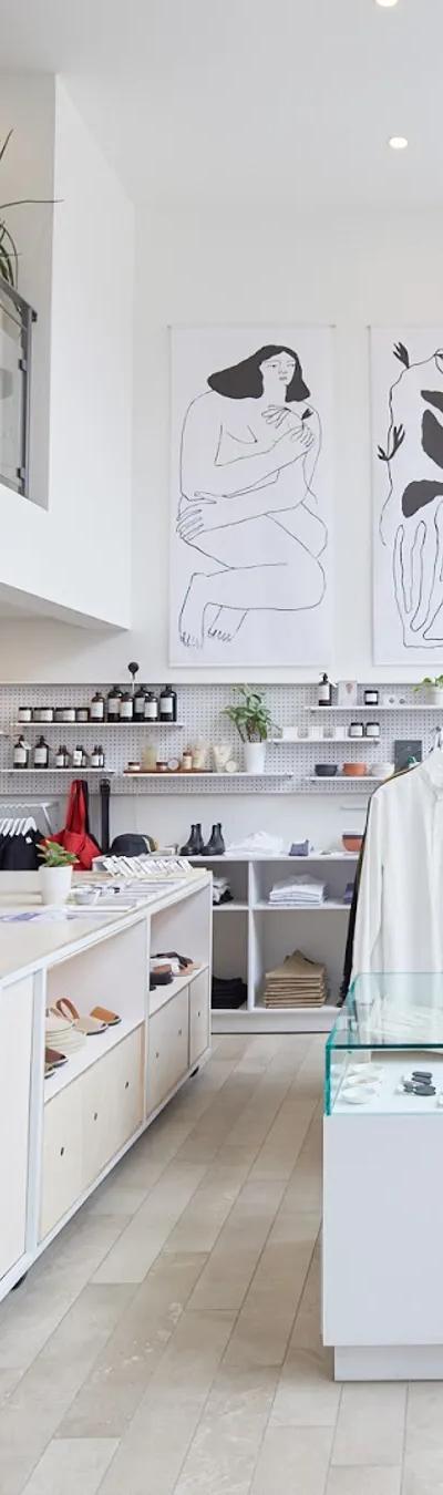 The bright interior of a Montreal atelier-boutique with white racks of clothing and line-drawing artwork