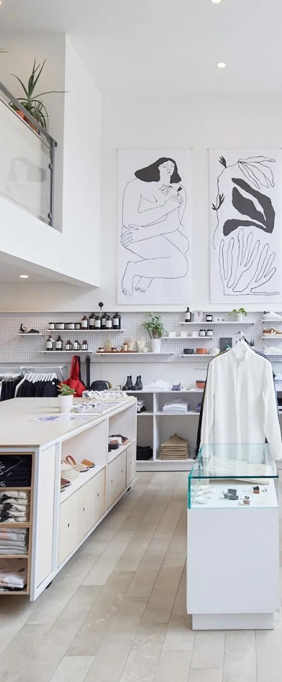 The bright interior of a Montreal atelier-boutique with white racks of clothing and line-drawing artwork